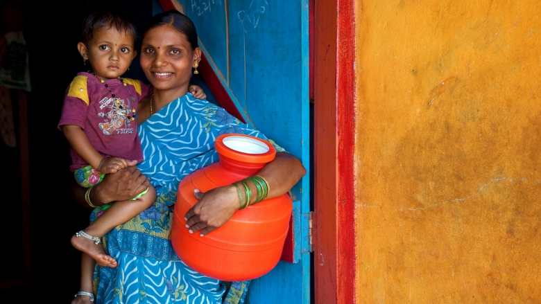 23 May 2013, Bekkinakeri Village, Karnataka, India:  Geeta Bhogan (23) with her daughter Renuka at the family home in Bekkinakeri Village that she shares with family members and five cows. Eight months pregnant ,she says water collection took up a great deal of time and effort costing lost opportunity to get ahead. Since the installation of a tap one year ago she says her life has changed for the better. The family have paid 7000 rupees to have a toilet installed and since then she says their hygiene has improved greatly. The World Bank Rural Water Supply and Sanitation project (RWSS) is helping the villagers of Bekkinakeri Village who have faced an acute shortage of drinking water. Many have had to travel up to 2km to a well outside the village to get access to clean water. The result is water collection takes away time that could be better spent earning wages or working the fields. Now taps have been installed outside peoples homes and for two hours each day the residents are able to get all they need. As well as water supply the project focuses on supply of toilets to people who have always defecated in the open. The aim has been to reduce hygiene issues and improve lives and residents are embracing the opportunities offered by the Bank projects. Picture by Graham Crouch/World Bank